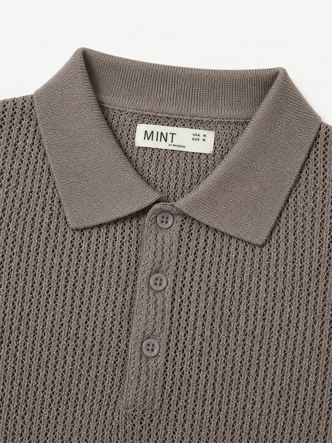 Close-up of a Brown knit polo shirt with a collar and buttons, featuring the brand 'Mint'.