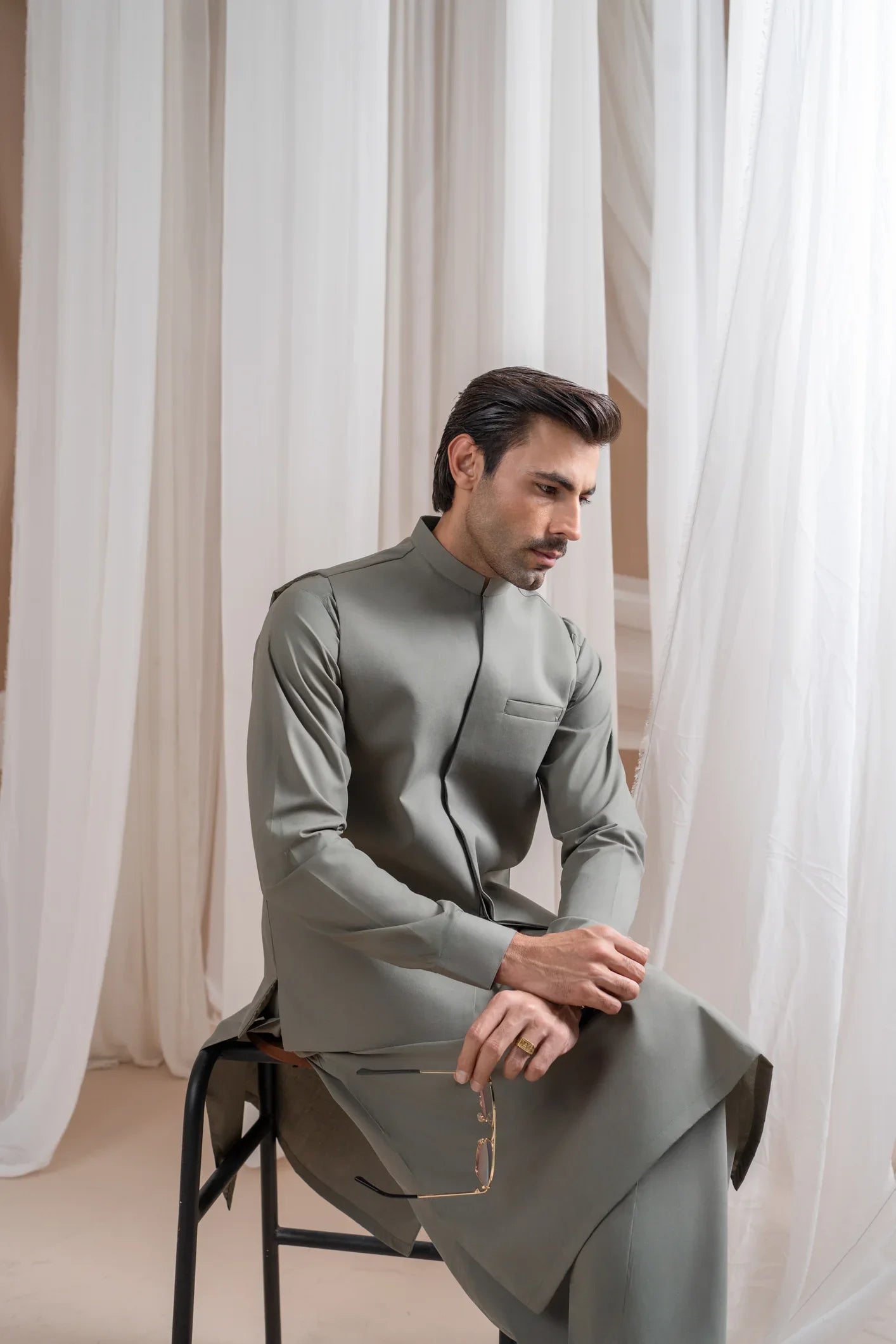 A man wearing a sand grey luxury formal Kameez Shalwar with a straight cut waistcoat and a patch pocket waistcoat.