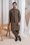 A man wearing a light brown luxury formal Kameez Shalwar with a straight cut and a patch pocket waistcoat.