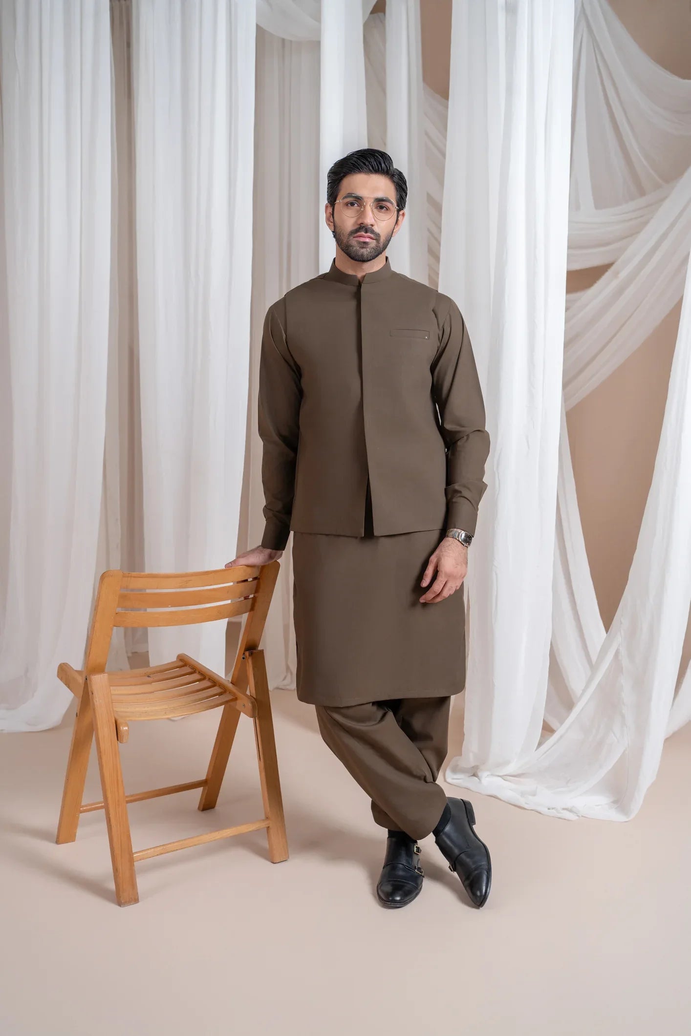 A man standing wearing a light brown straight cut luxury blended waistcoat with a mandarin collar and full sleeves.
