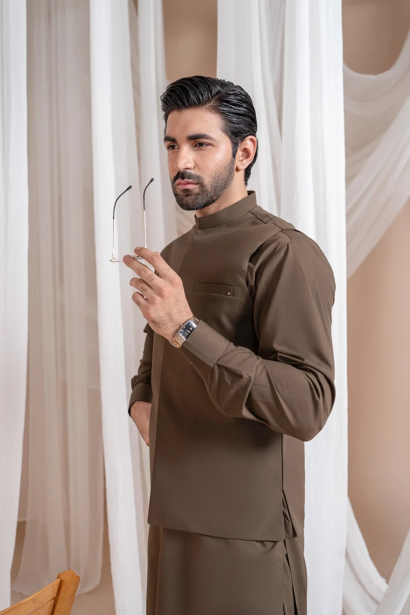 A man standing wearing a light brown straight cut luxury blended waistcoat with a mandarin collar and full sleeves.