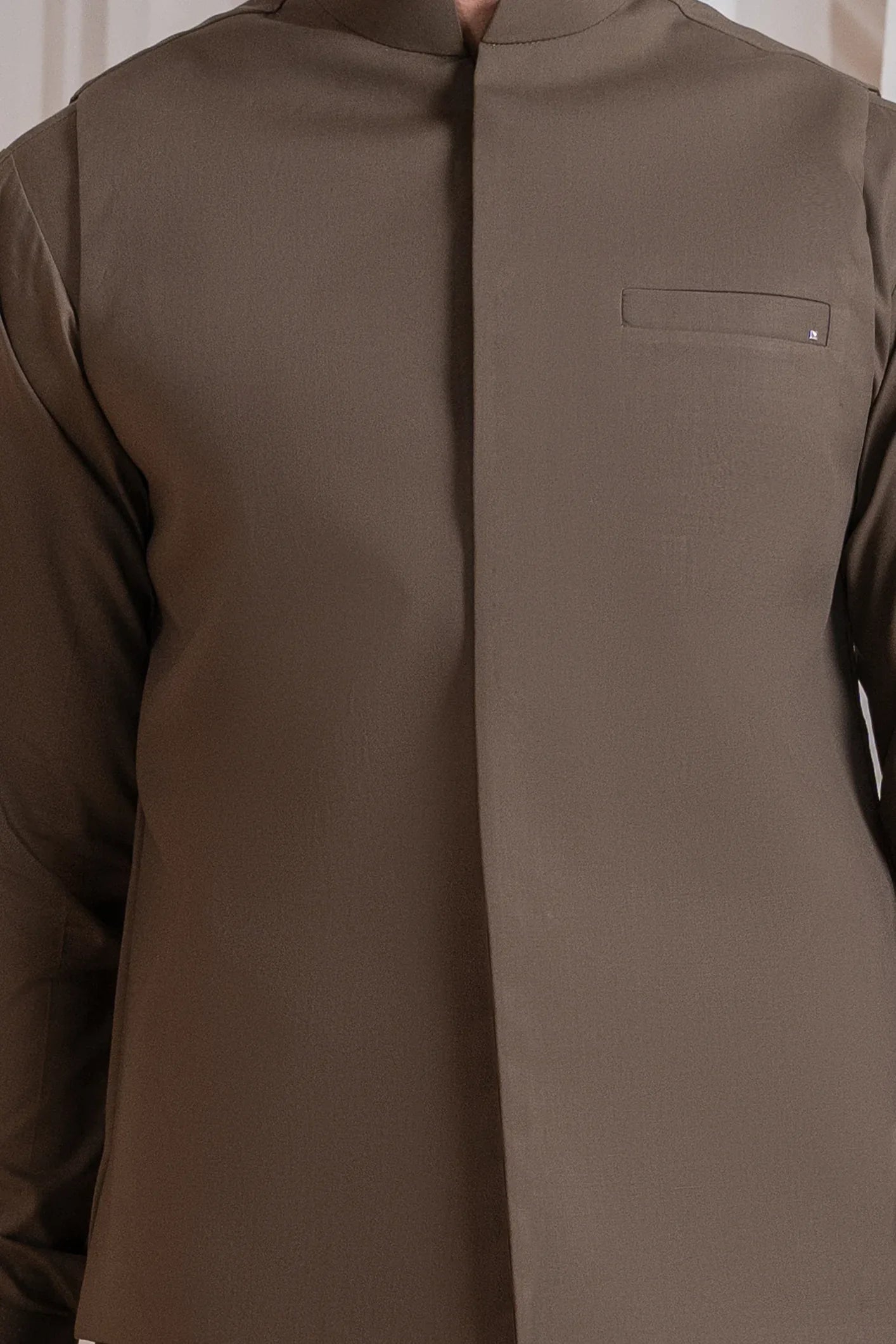 A man wearing a light brown luxury formal Kameez Shalwar with a straight cut and a patch pocket waistcoat.