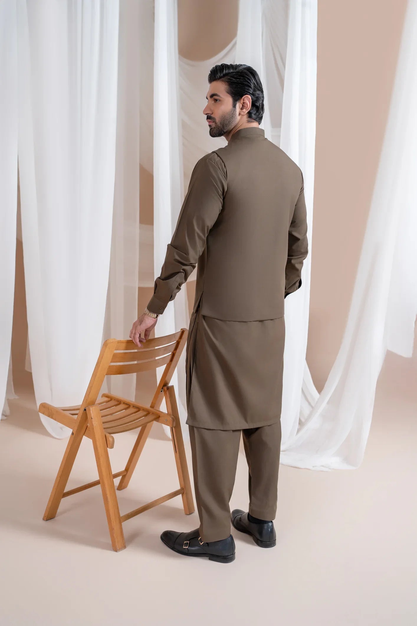 A man standing wearing a light brown straight cut luxury blended waistcoat with a mandarin collar and full sleeves.