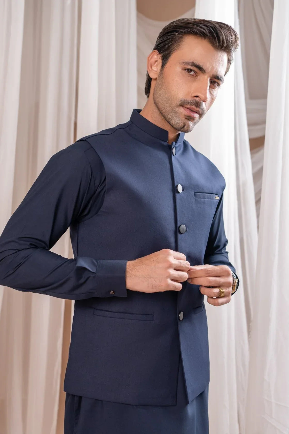 A man wearing a navy blue suiting buttoned waistcoat with a straight cut design.