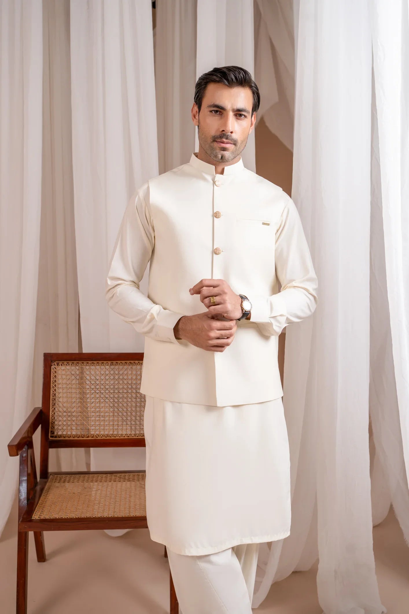 A man wearing a Bosky White luxury blended waistcoat with a mandarin collar and straight cut buttoned design, paired with kameez shalwar and trousers.