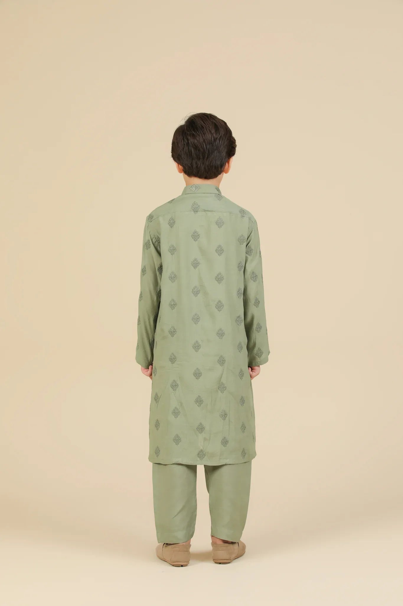 Child wearing a mint green raw silk embroidered kurta trouser with a beige background