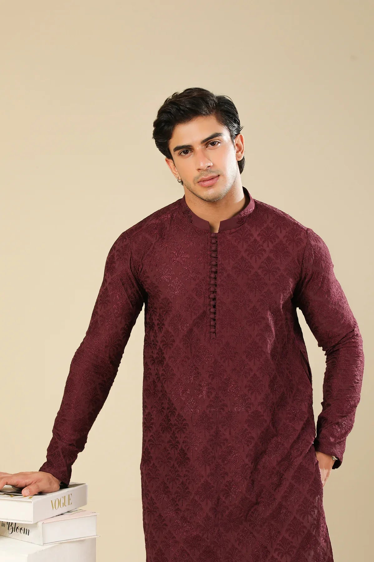 Man wearing a maroon embroidered kurta trouser with a beige background