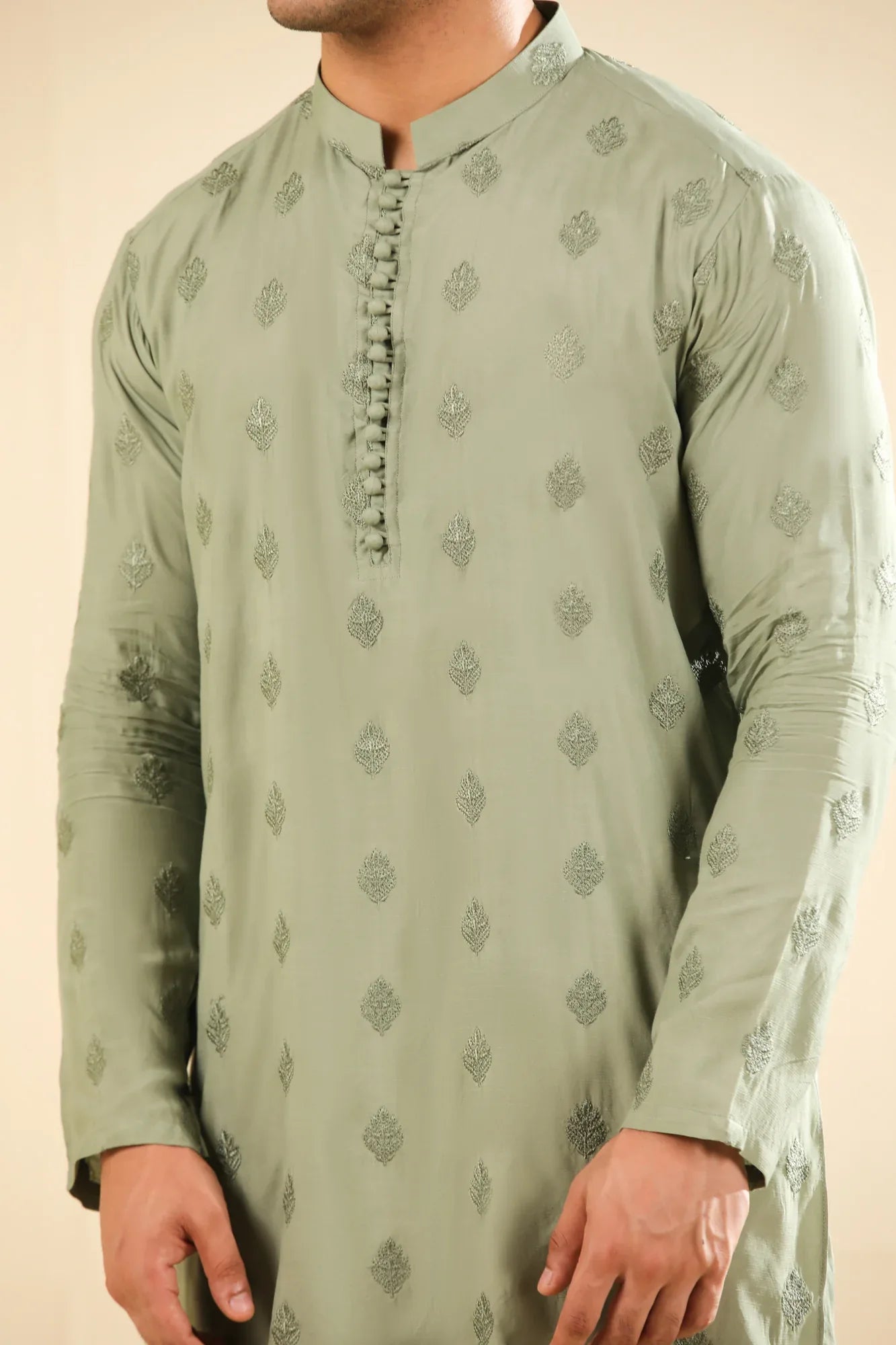 Man wearing a light green raw silk embroidered kurta with a beige backgroung