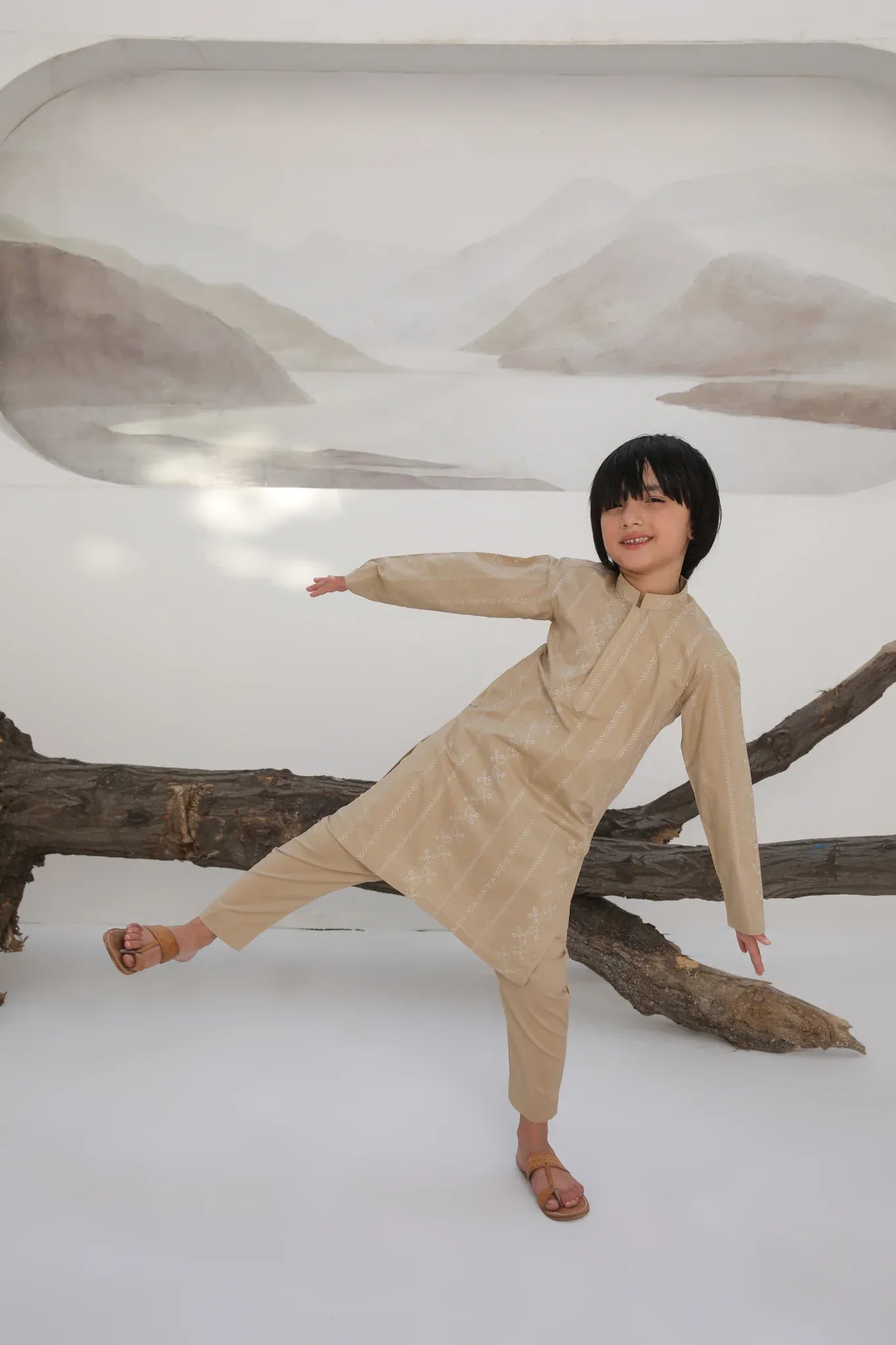 A child wearing a beige embroidered cotton kurta with a mandarin collar and full sleeves, paired with plain beige cotton trousers.
