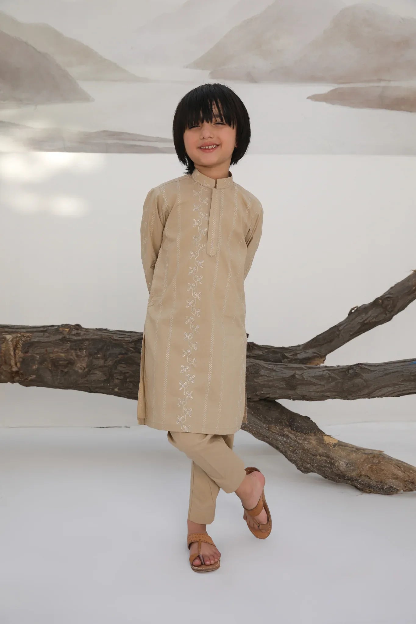 A child wearing a beige embroidered cotton kurta with a mandarin collar and full sleeves, paired with plain beige cotton trousers.