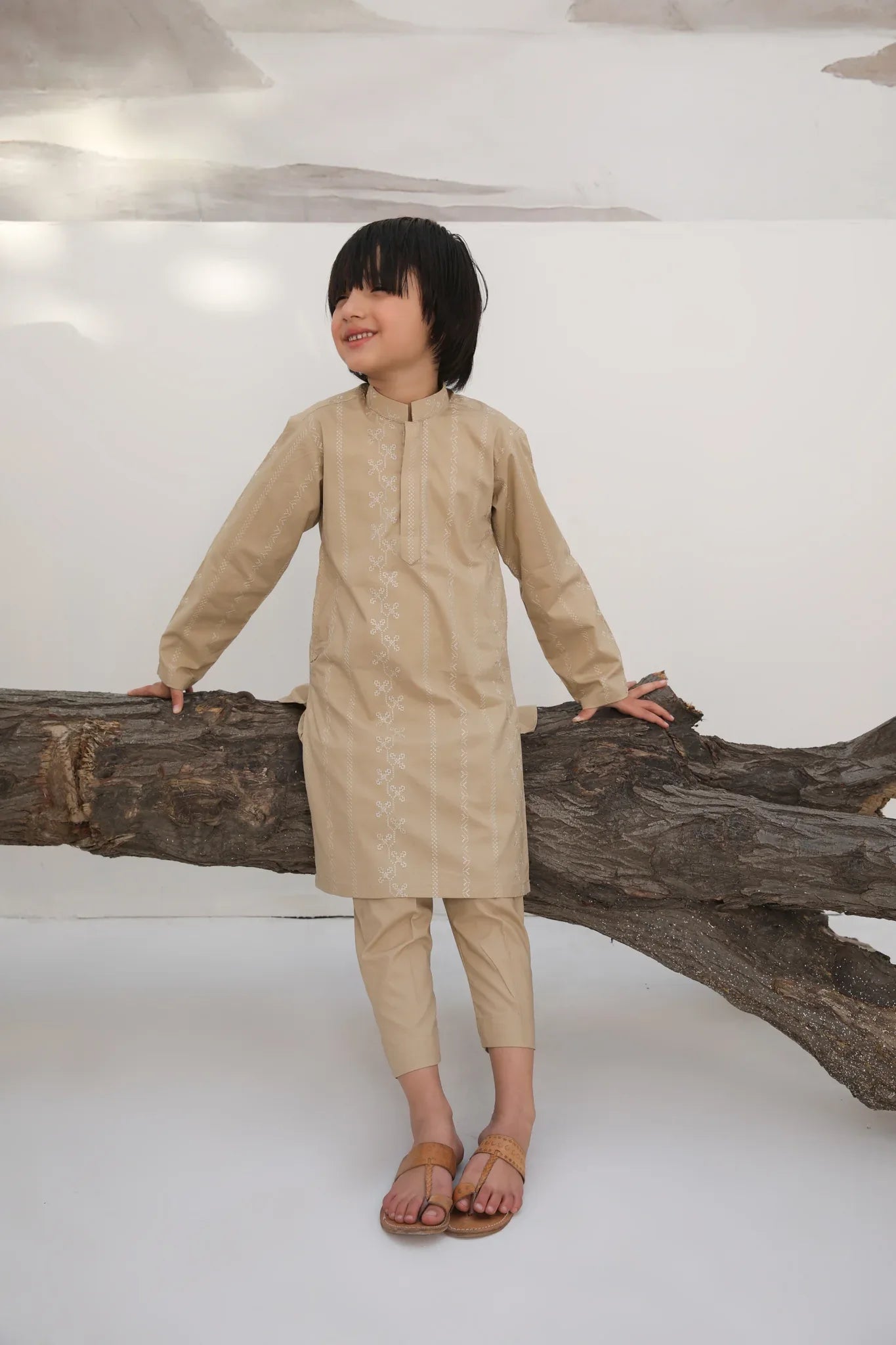 A child wearing a beige embroidered cotton kurta with a mandarin collar and full sleeves, paired with plain beige cotton trousers.