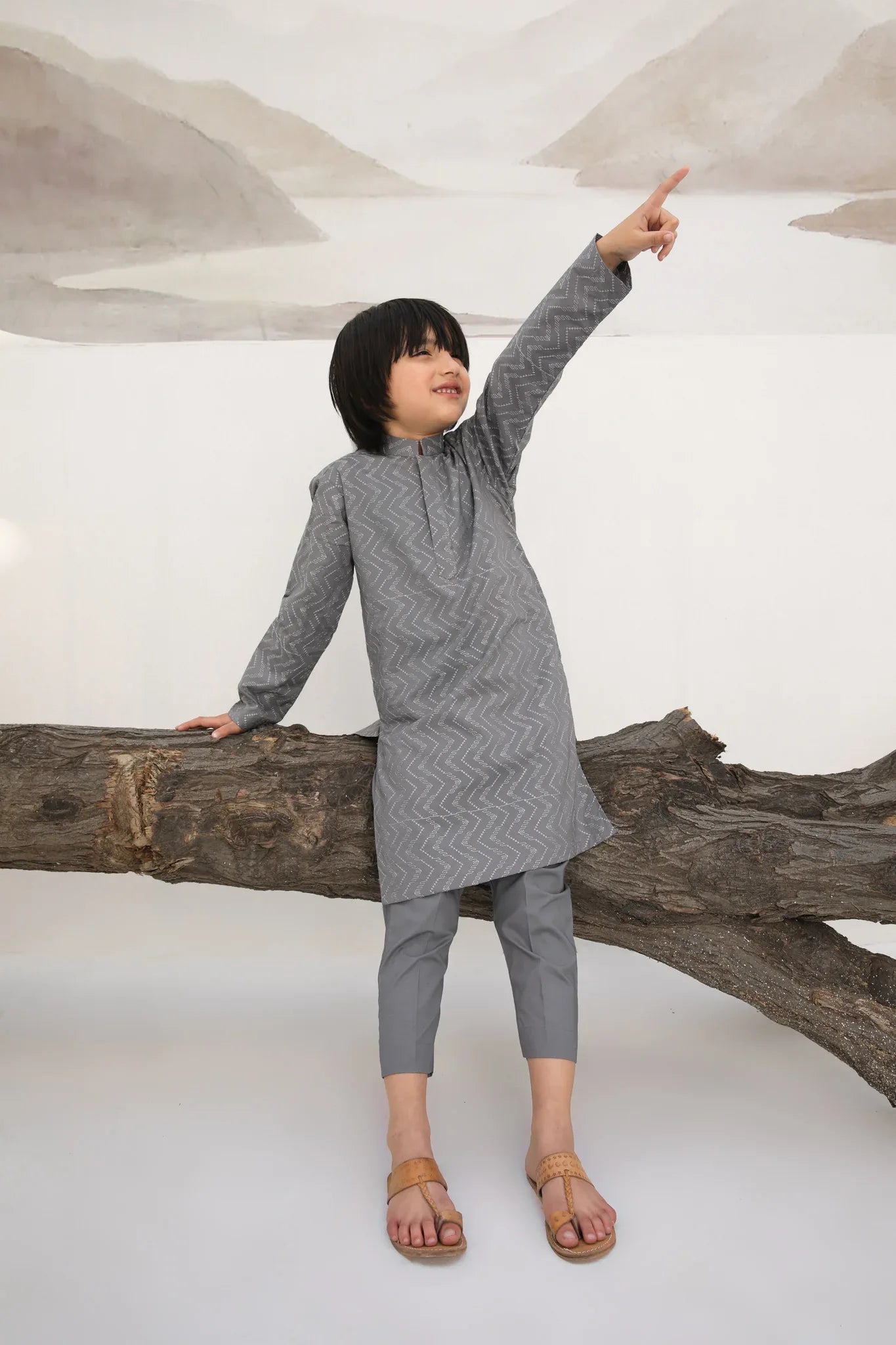 A child wearing a light grey embroidered kurta with a mandarin collar and full sleeves, paired with plain cotton trousers.