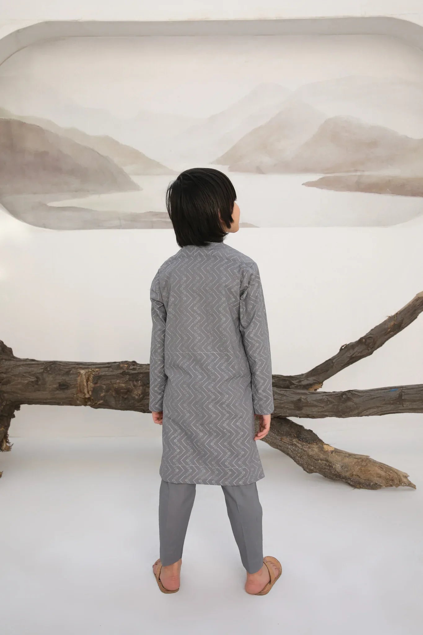 A child wearing a light grey embroidered kurta with a mandarin collar and full sleeves, paired with plain cotton trousers.