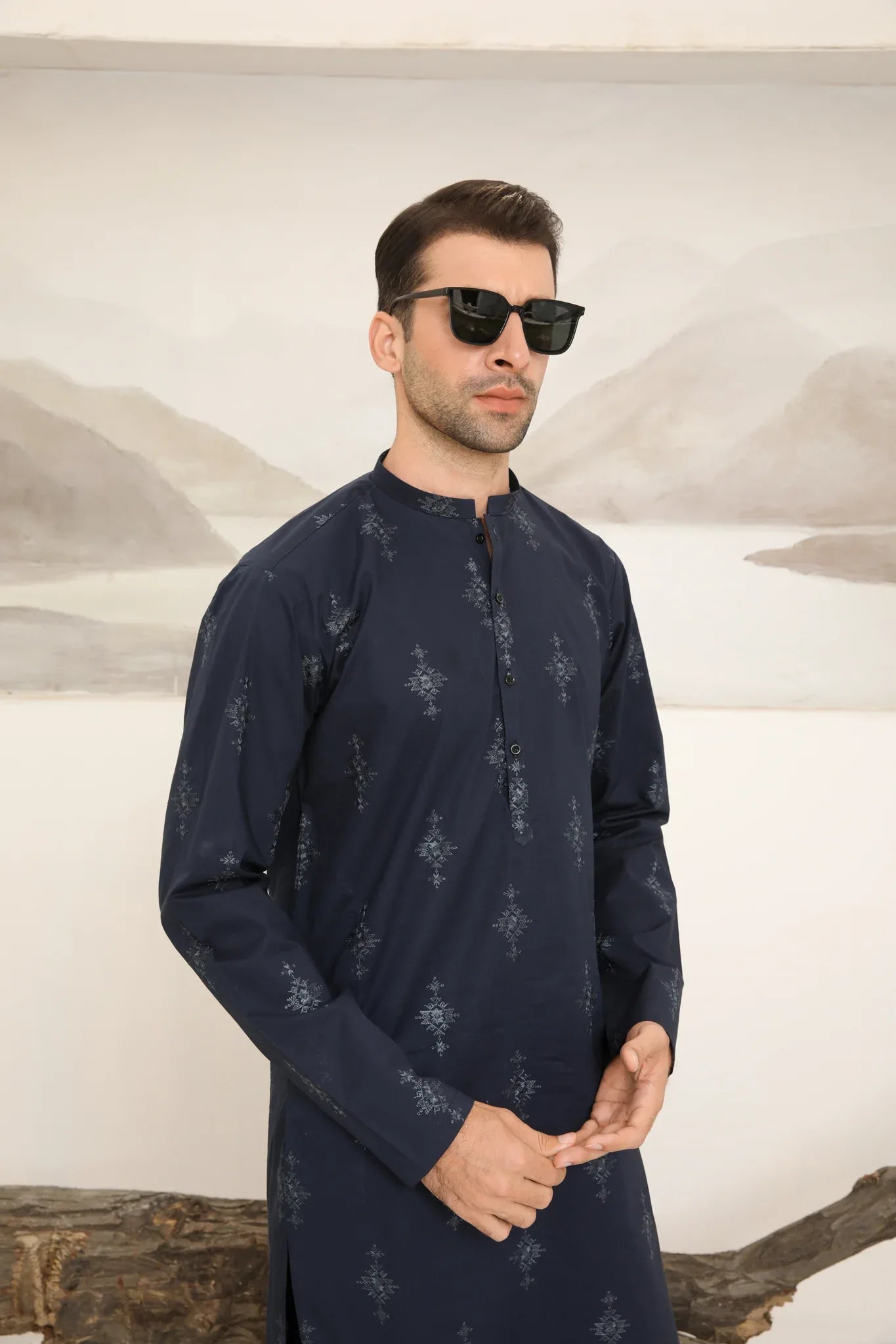 A man wearing a navy blue cotton embroidered kurta and trouser with a mandarin collar and full sleeves.