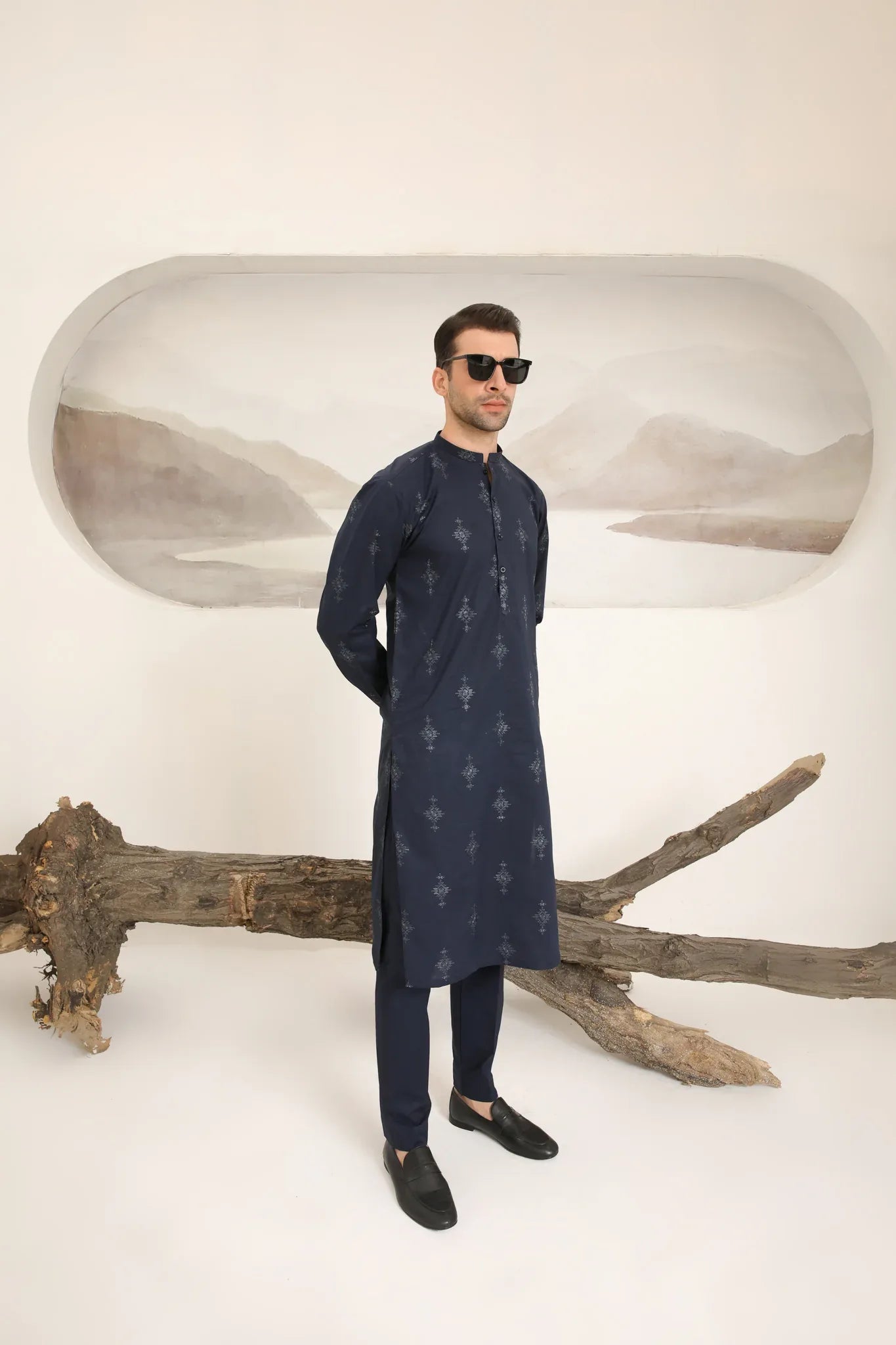 A man wearing a navy blue cotton embroidered kurta and trouser with a mandarin collar and full sleeves.