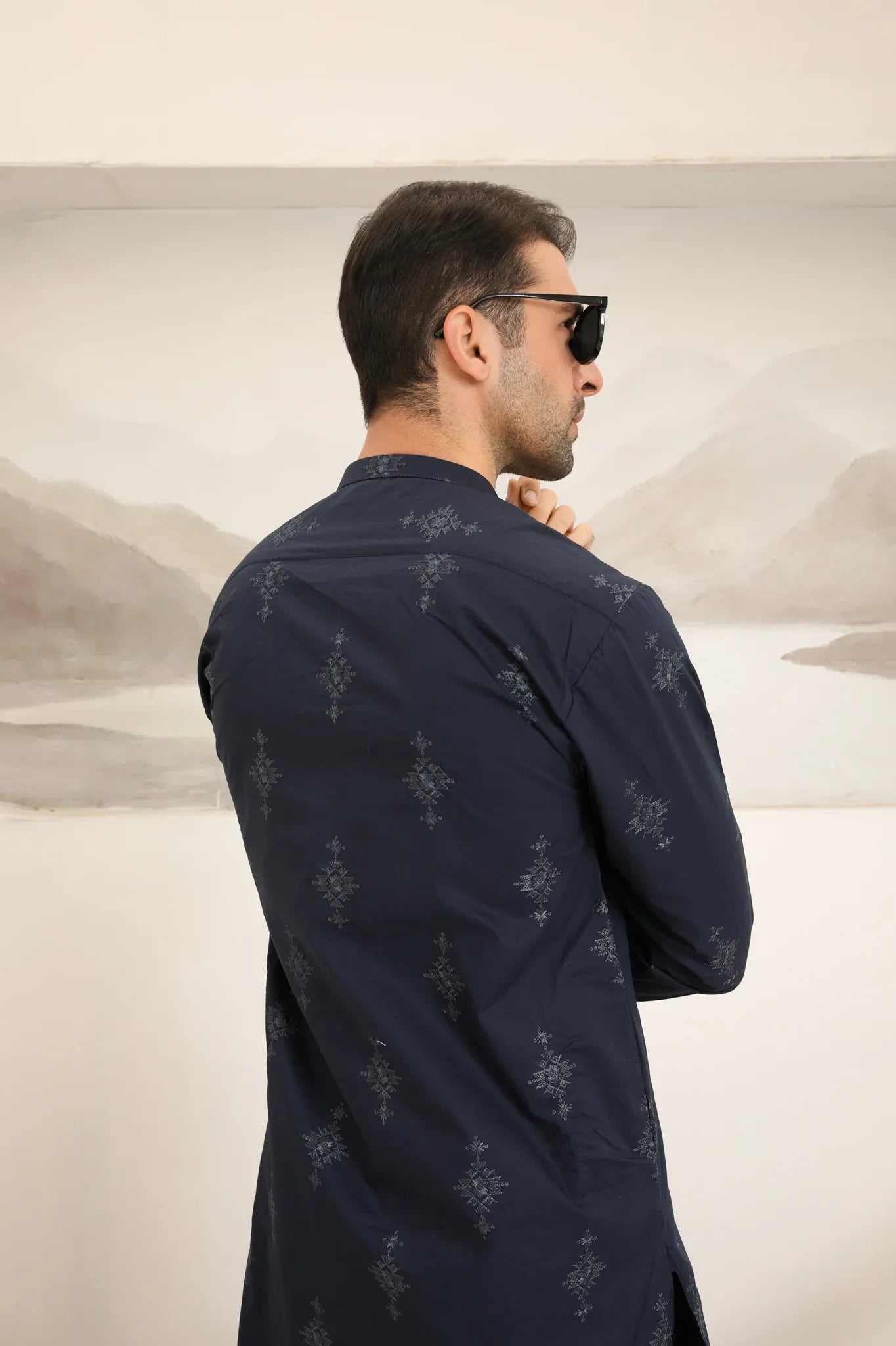A man wearing a navy blue cotton embroidered kurta and trouser with a mandarin collar and full sleeves.