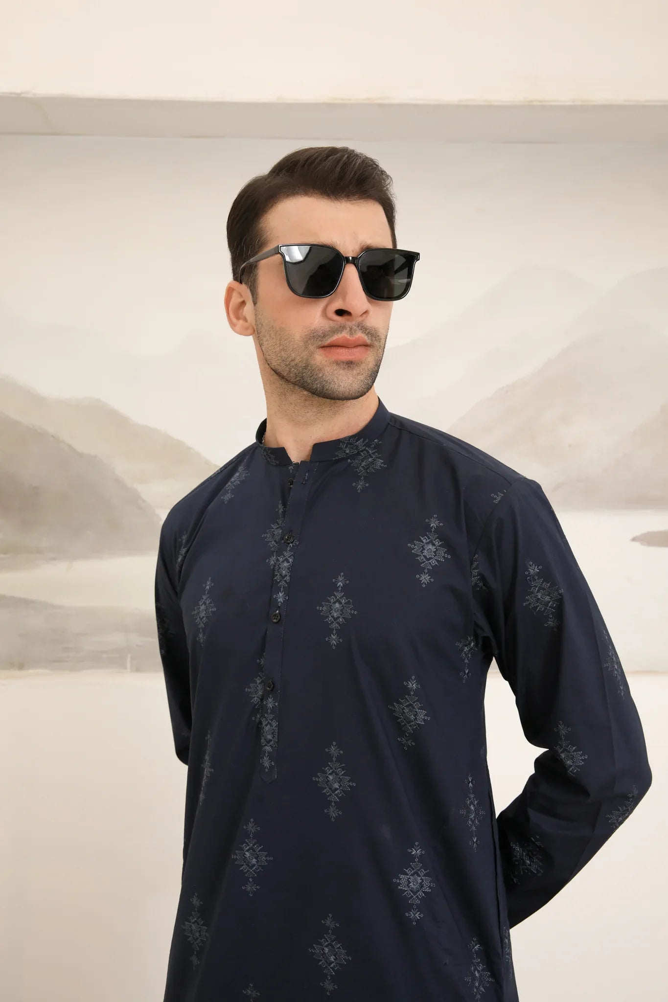 A man wearing a navy blue cotton embroidered kurta and trouser with a mandarin collar and full sleeves.