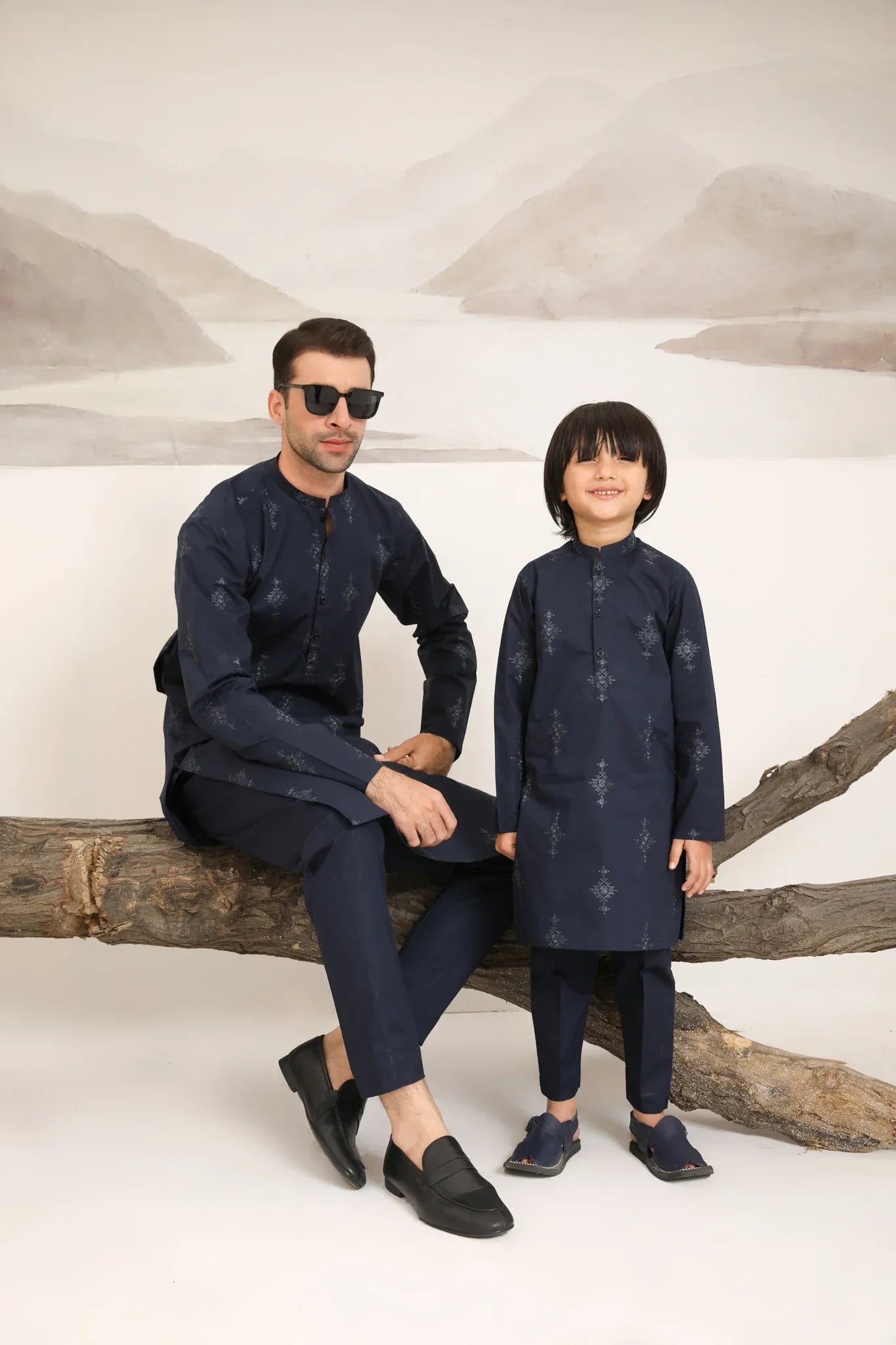A man and a boy wearing a navy blue cotton embroidered kurta and trouser with a mandarin collar and full sleeves.