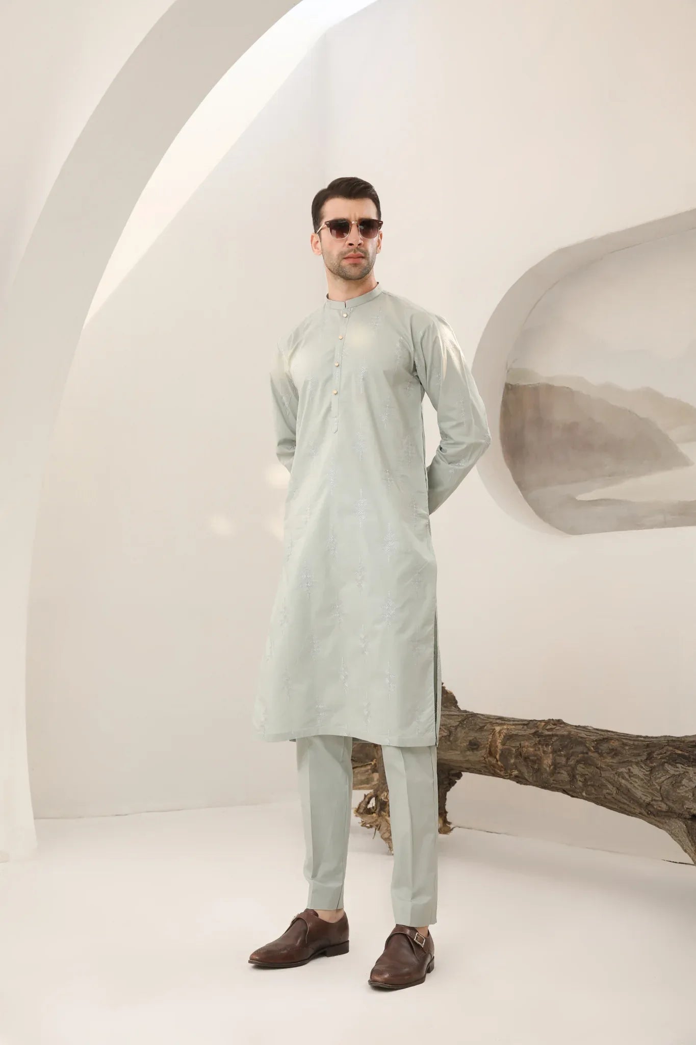 A man wearing a mint green embroidered kurta with full sleeves and a mandarin collar, paired with plain trousers.