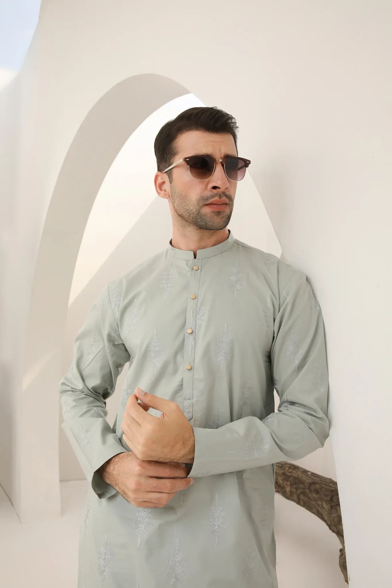 A man wearing a mint green embroidered kurta with full sleeves and a mandarin collar, paired with plain trousers.