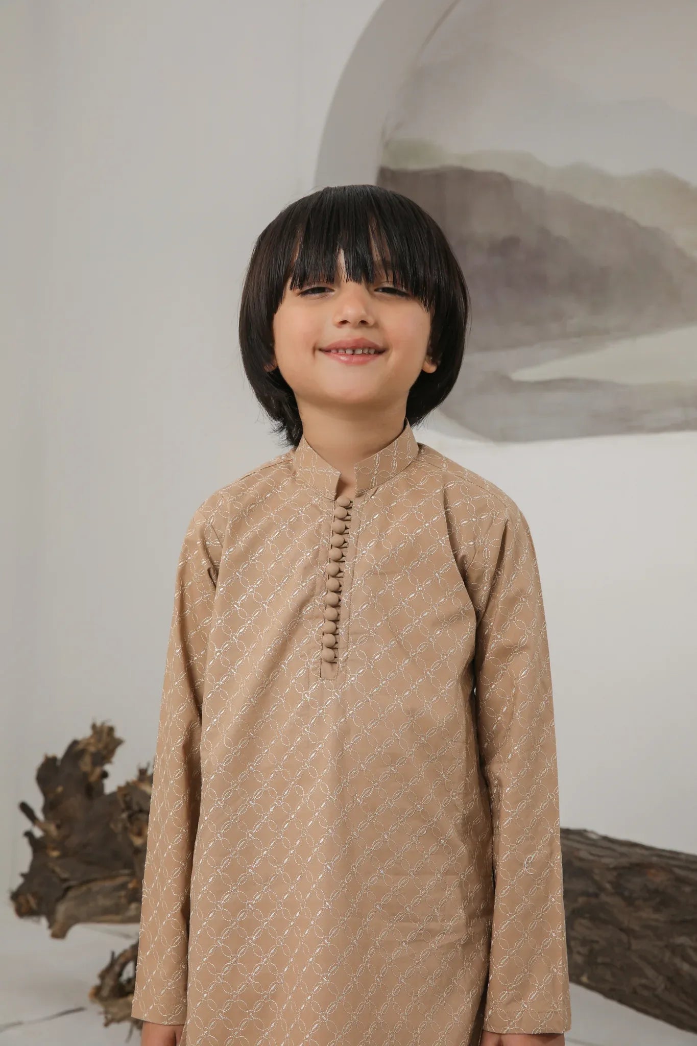 A child wearing a camel embroidered cotton kurta and trouser with a mandarin collar.