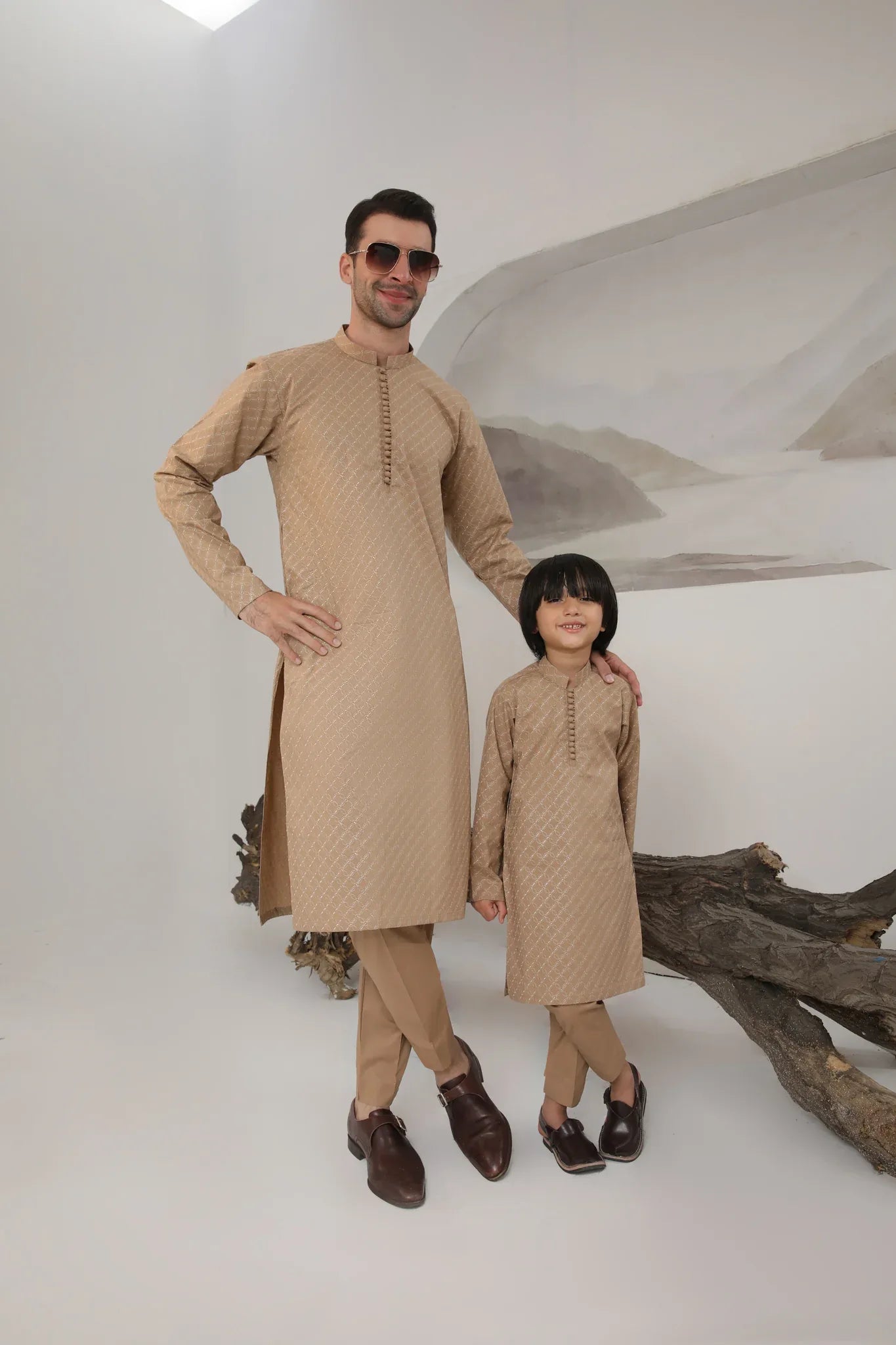 A man wearing a camel cotton embroidered kurta with full sleeves and a mandarin collar, paired with plain trousers.