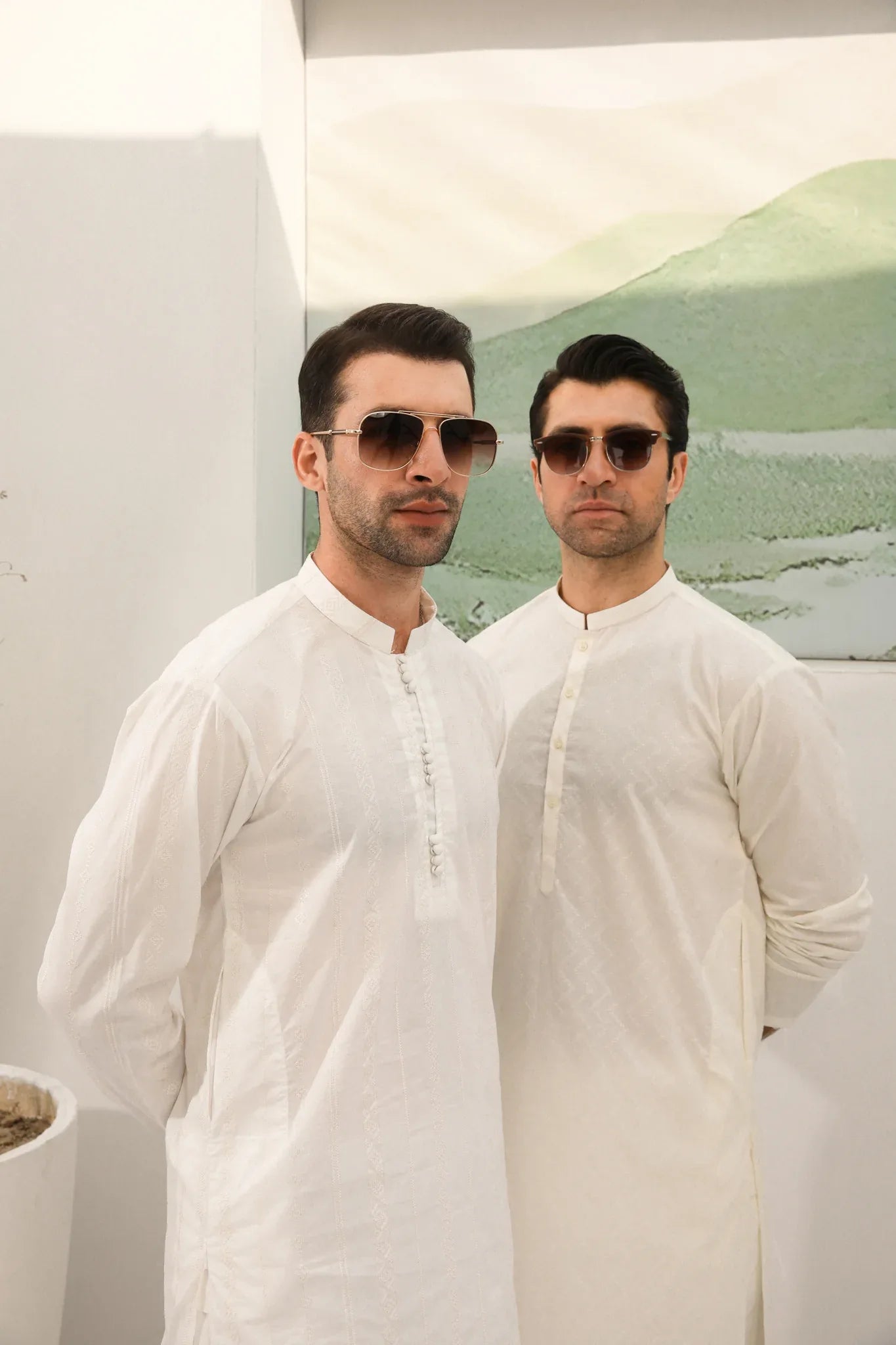 A man wearing a bsoky white cotton kurta embroidered with geometric patterns, featuring a mandarin collar and full sleeves, paired with plain trousers.