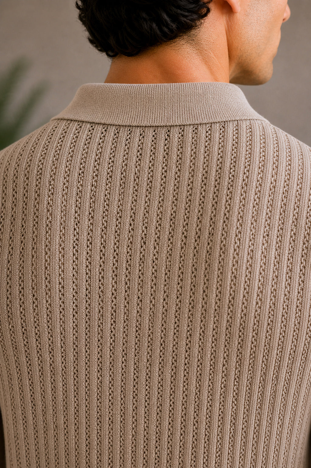 Close-up of a person wearing a beige knitted sweater with a blurred background