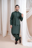 A man wearing a green luxury blended waistcoat with a mandarin collar and straight cut design, standing in a room with white drapes in the background.