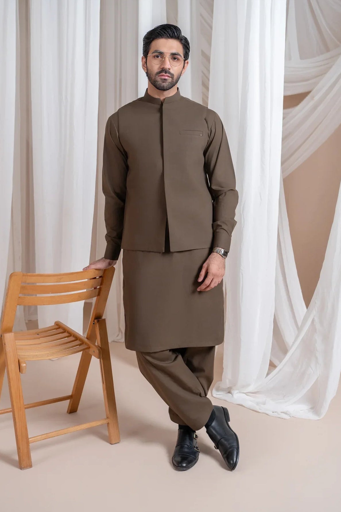A man wearing a light brown luxury formal Kameez Shalwar with a straight cut and a patch pocket waistcoat.