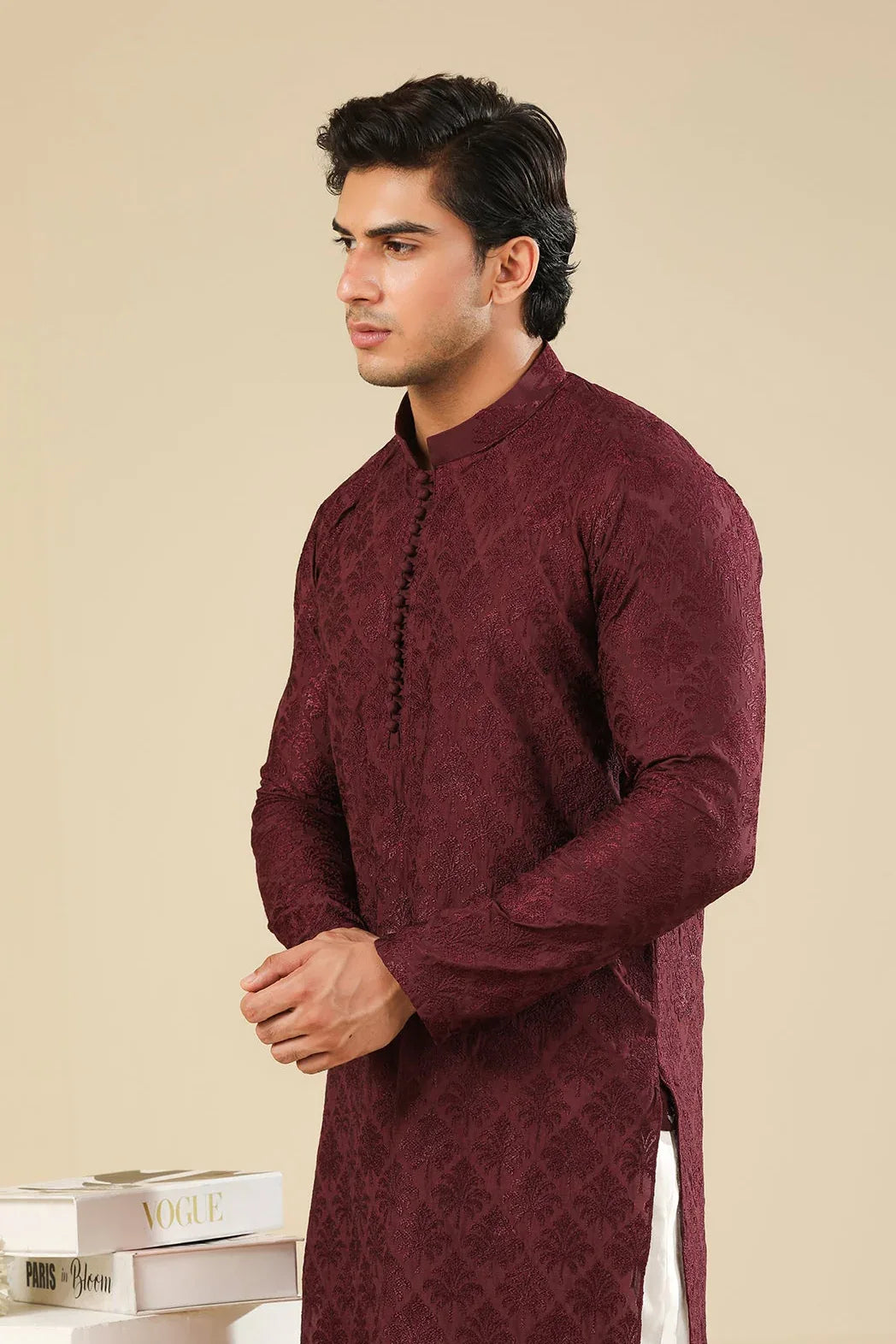 Man wearing a maroon embroidered kurta trouser with a beige background