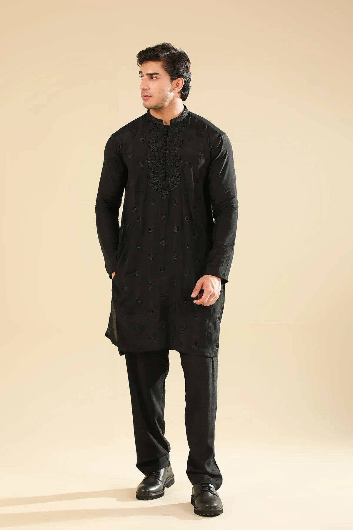 Man wearing a black raw silk embroidered kurta trouser against a beige background