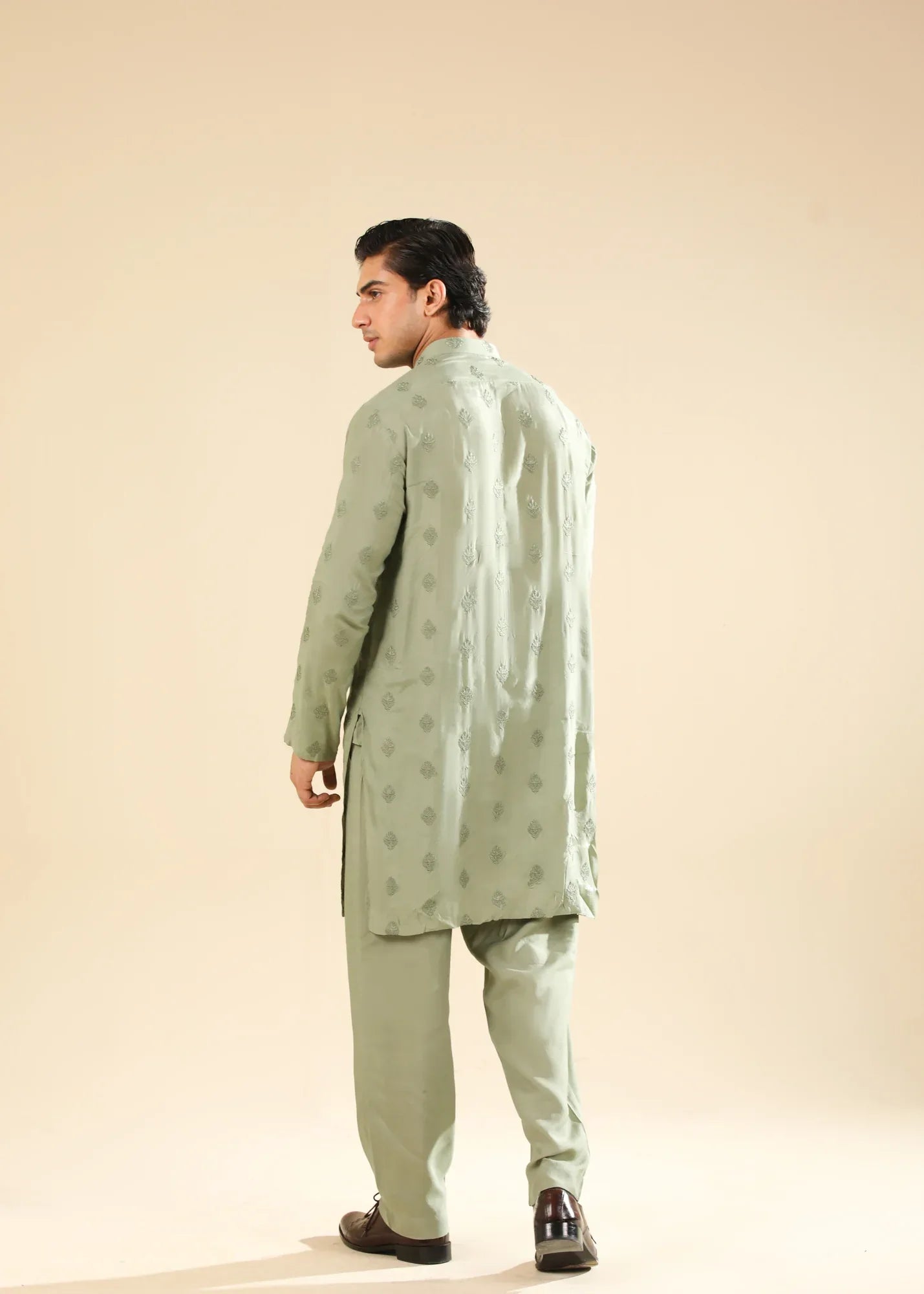 Man wearing a light green raw silk embroidered kurta with a beige backgroung